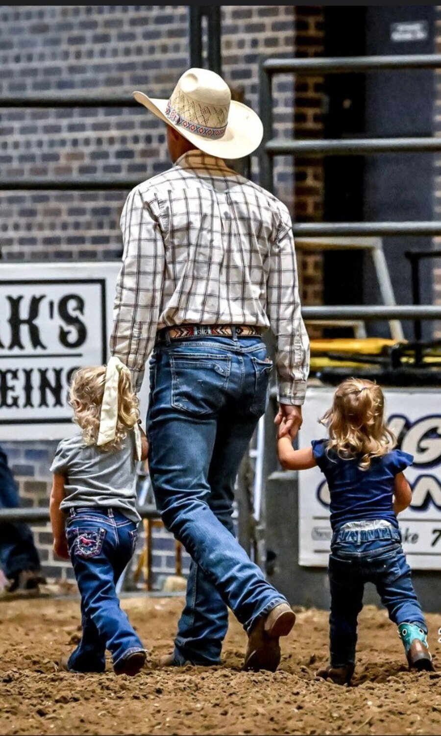 Jon Anderson walking hand-in-hand with his two daughters at a rodeo
