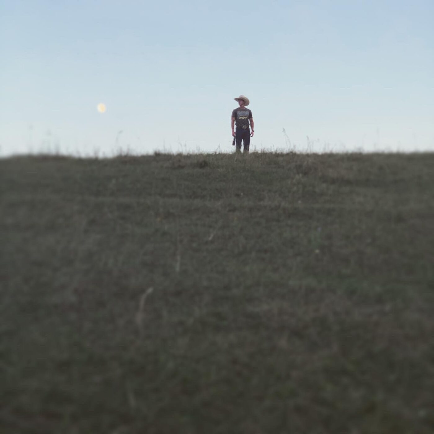 A lone figure standing on a hilltop at dusk